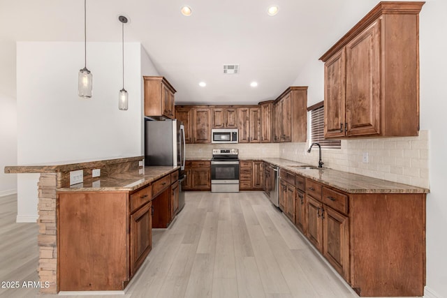 kitchen with stone counters, sink, light hardwood / wood-style flooring, pendant lighting, and appliances with stainless steel finishes