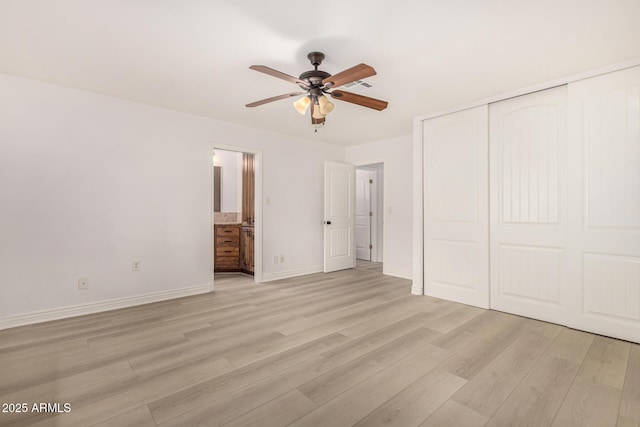 unfurnished bedroom featuring ensuite bath, ceiling fan, light wood-type flooring, and a closet