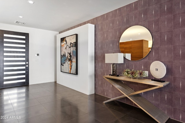 foyer featuring tile walls and dark tile patterned flooring