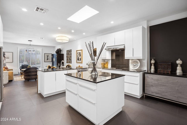 kitchen with a kitchen island, white cabinetry, hanging light fixtures, and tasteful backsplash