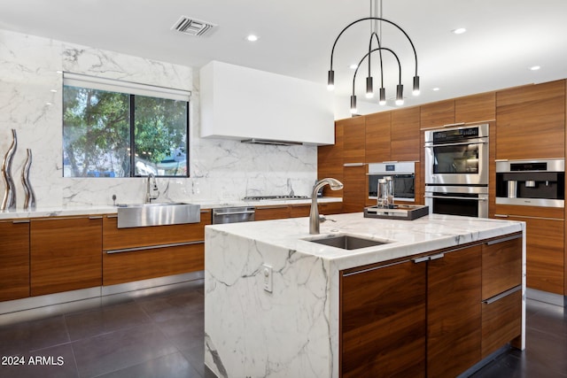 kitchen featuring sink, stainless steel appliances, a kitchen island with sink, and decorative light fixtures