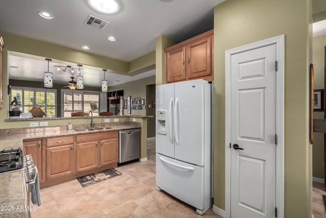 kitchen with visible vents, a sink, appliances with stainless steel finishes, a peninsula, and hanging light fixtures