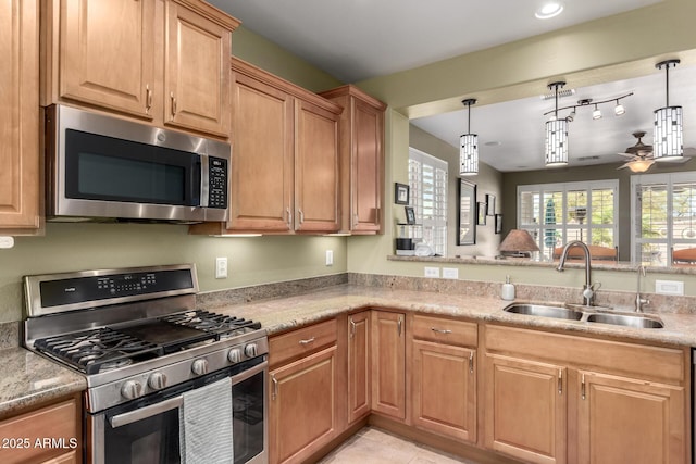 kitchen featuring light tile patterned floors, ceiling fan, hanging light fixtures, a sink, and appliances with stainless steel finishes