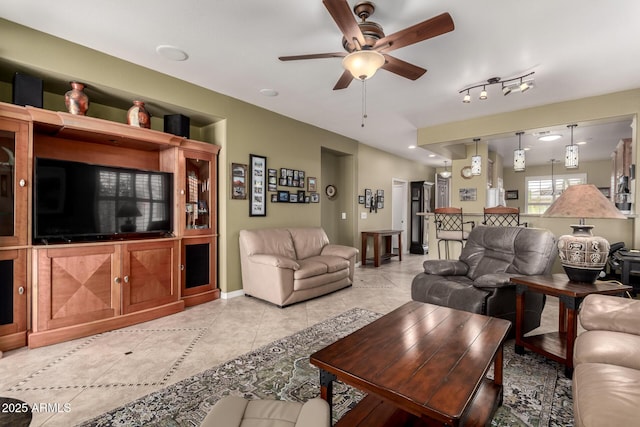 living room featuring light tile patterned floors, baseboards, and a ceiling fan