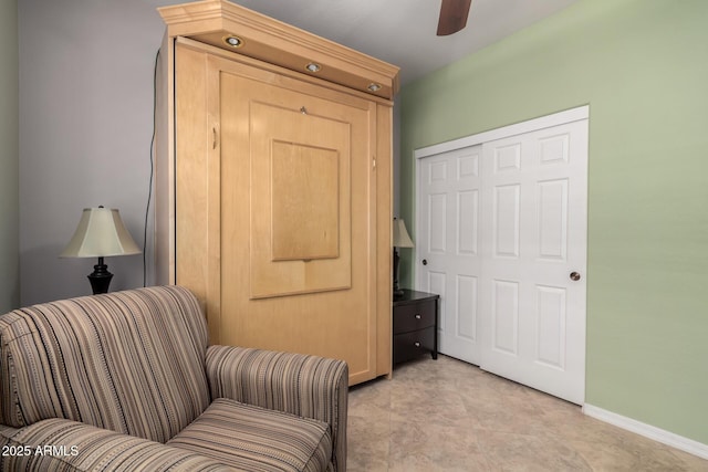 sitting room with a ceiling fan and baseboards