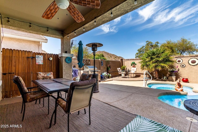 view of patio / terrace with outdoor dining space, a fenced in pool, an in ground hot tub, a fenced backyard, and ceiling fan