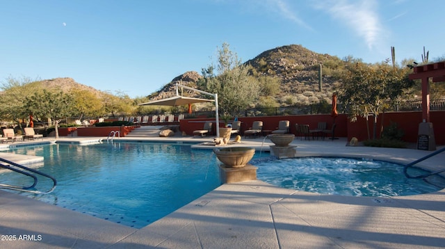 community pool with a mountain view, fence, a hot tub, and a patio area