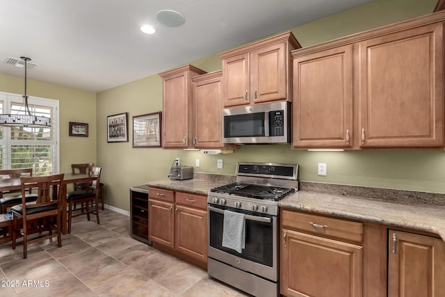 kitchen with baseboards, visible vents, hanging light fixtures, wine cooler, and appliances with stainless steel finishes