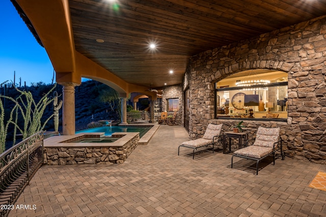 patio terrace at twilight featuring a pool with hot tub