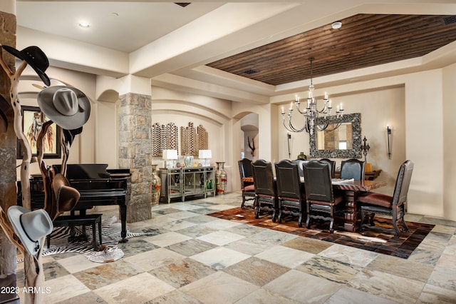 tiled dining area with an inviting chandelier, decorative columns, wood ceiling, and a tray ceiling