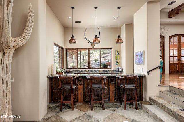 bar featuring hanging light fixtures, light wood-type flooring, and stone countertops