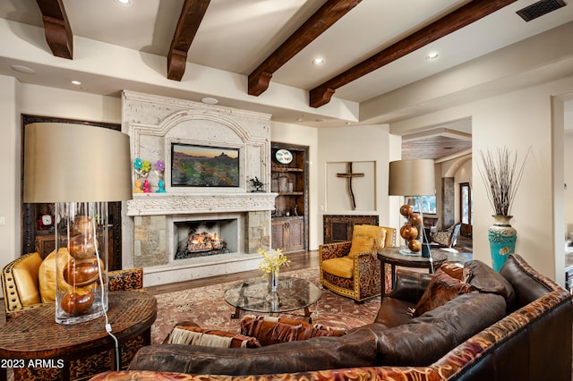 living room with built in features, hardwood / wood-style floors, and beamed ceiling