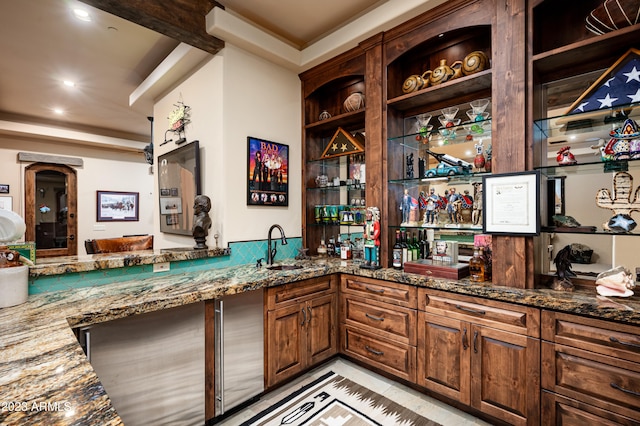 bar featuring sink, beam ceiling, dark stone countertops, and light tile floors