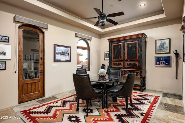 tiled dining room featuring a raised ceiling and ceiling fan