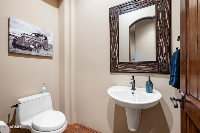 bathroom with toilet and hardwood / wood-style flooring