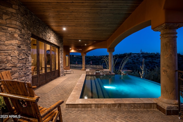 pool at night featuring a patio