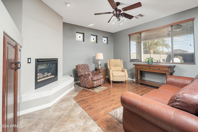 living room featuring ceiling fan and a fireplace