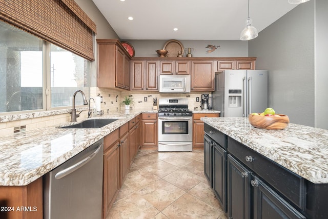 kitchen with appliances with stainless steel finishes, backsplash, light stone countertops, a kitchen island, and sink