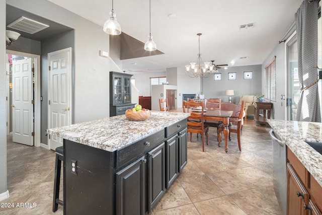 kitchen featuring dishwasher, pendant lighting, a kitchen island, a wealth of natural light, and light stone counters