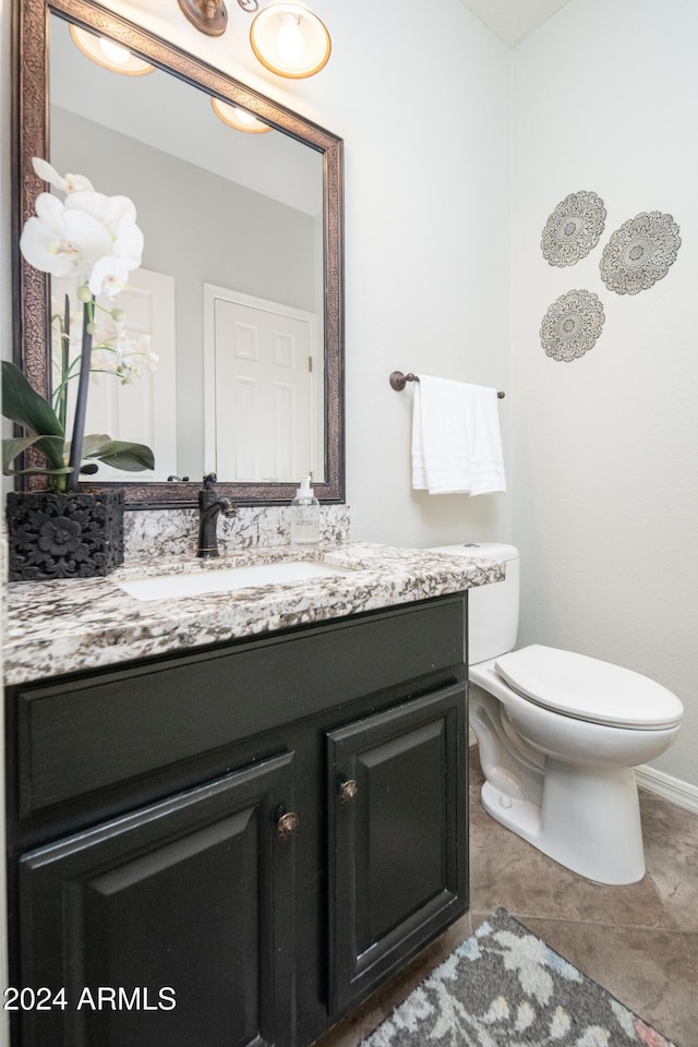 bathroom with toilet, vanity, and tile patterned floors