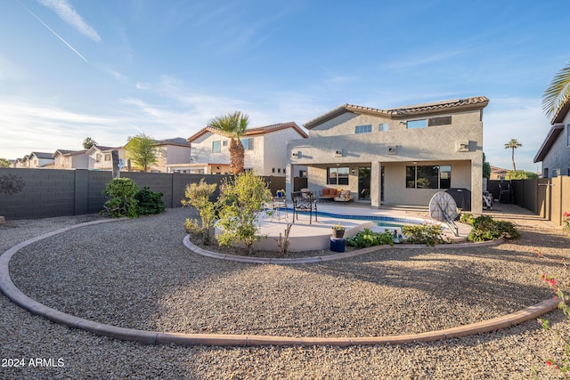 rear view of house with a fenced in pool and a patio