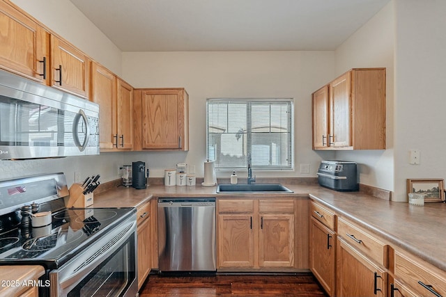 kitchen featuring light countertops, appliances with stainless steel finishes, a sink, and dark wood finished floors