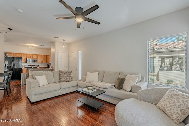 living area featuring dark wood-style flooring, visible vents, and a ceiling fan