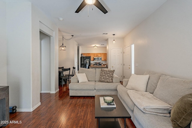 living room with dark wood-style floors, visible vents, baseboards, and a ceiling fan