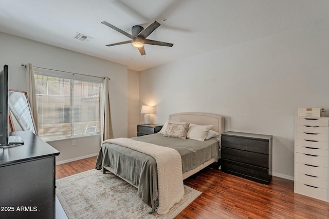 bedroom with a ceiling fan, wood finished floors, visible vents, and baseboards