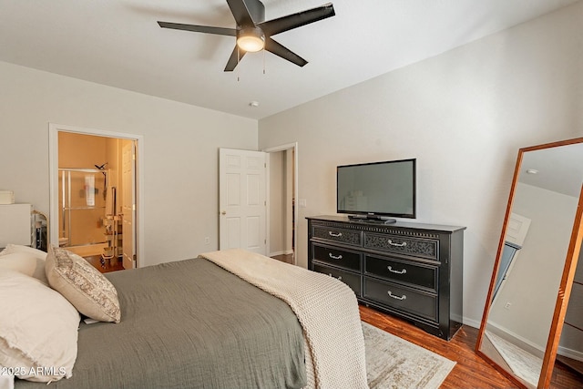 bedroom with baseboards, ceiling fan, ensuite bath, and wood finished floors