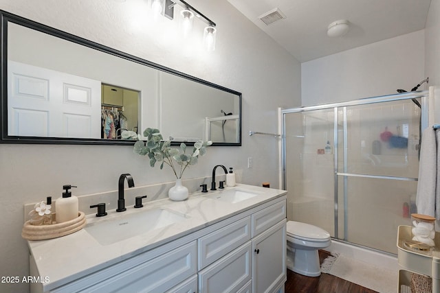 full bathroom featuring toilet, a sink, visible vents, and a shower stall