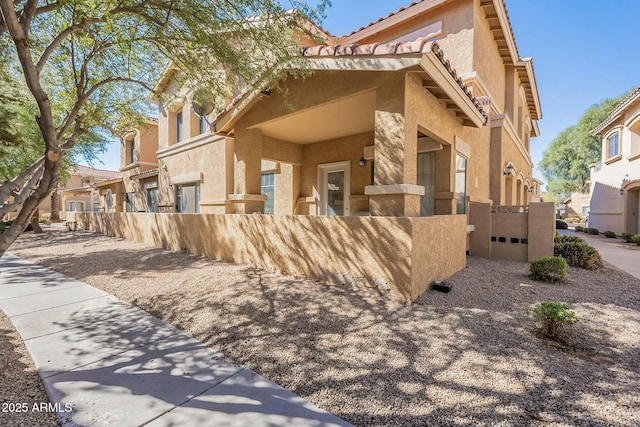 view of side of property featuring a residential view, fence, and stucco siding