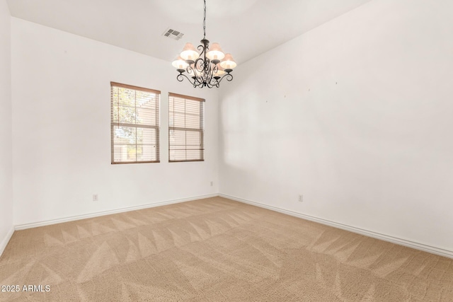 empty room featuring carpet floors and a chandelier