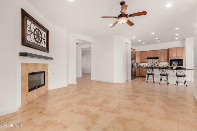 unfurnished living room featuring a tile fireplace and ceiling fan