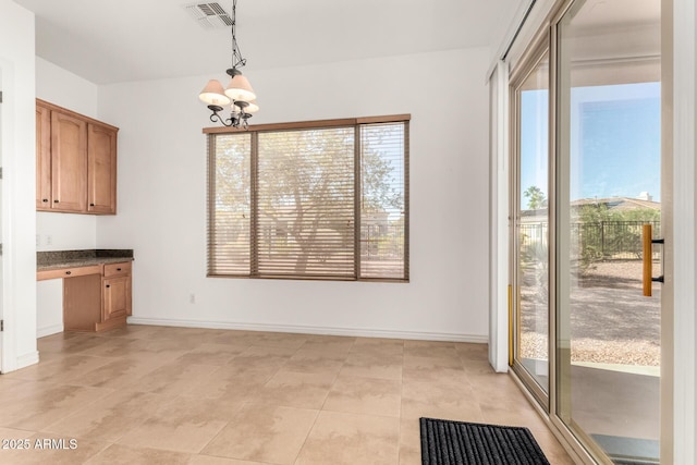 unfurnished dining area with plenty of natural light, built in desk, and a notable chandelier