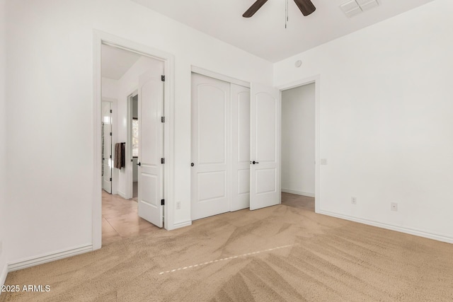 unfurnished bedroom featuring ceiling fan, light colored carpet, and a closet