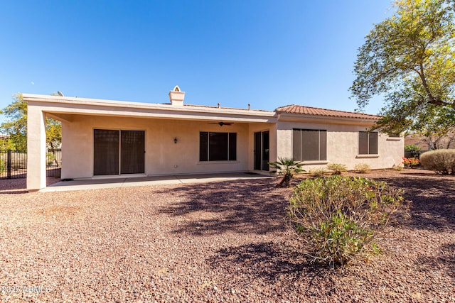 rear view of property featuring ceiling fan and a patio area