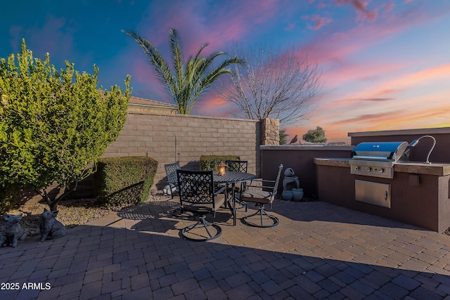 patio terrace at dusk with a grill and an outdoor kitchen