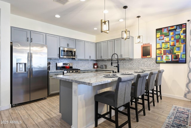 19560 W Valle Vista Way, Litchfield Park, AZ 85340 - kitchen featuring light stone countertops, gray cabinetry, a peninsula, light wood-style flooring, and appliances with stainless steel finishes