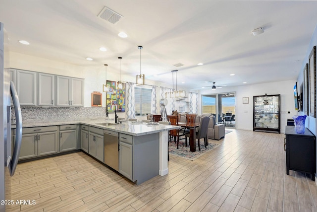 19560 W Valle Vista Way, Litchfield Park, AZ 85340 - kitchen featuring stainless steel appliances, a peninsula, a sink, visible vents, and gray cabinetry