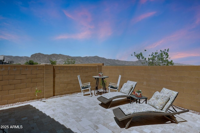 19560 W Valle Vista Way, Litchfield Park, AZ 85340 - patio terrace at dusk featuring a fenced backyard and a mountain view