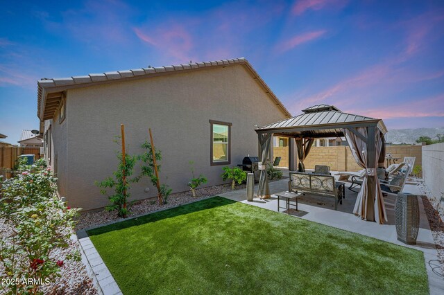 19560 W Valle Vista Way, Litchfield Park, AZ 85340 - back of house at dusk with a fenced backyard, an outdoor hangout area, a patio, a lawn, and a gazebo