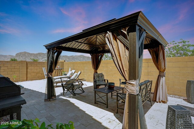 19560 W Valle Vista Way, Litchfield Park, AZ 85340 - patio terrace at dusk featuring a fenced backyard, a gazebo, and a mountain view