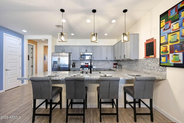 19560 W Valle Vista Way, Litchfield Park, AZ 85340 - kitchen with light stone countertops, a peninsula, backsplash, and appliances with stainless steel finishes