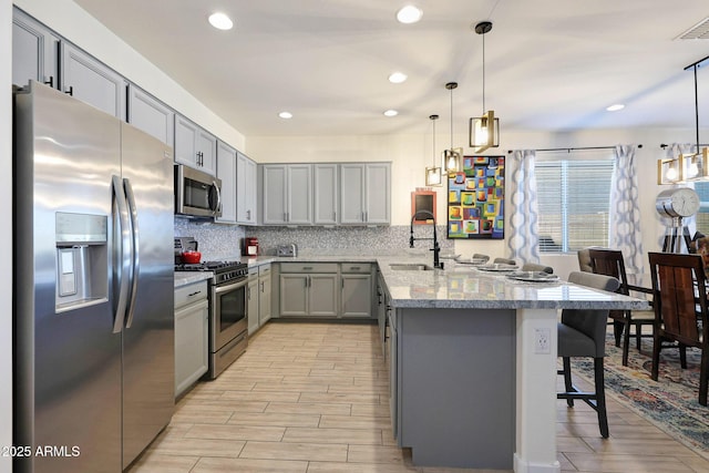 19560 W Valle Vista Way, Litchfield Park, AZ 85340 - kitchen featuring a peninsula, a sink, tasteful backsplash, gray cabinetry, and appliances with stainless steel finishes