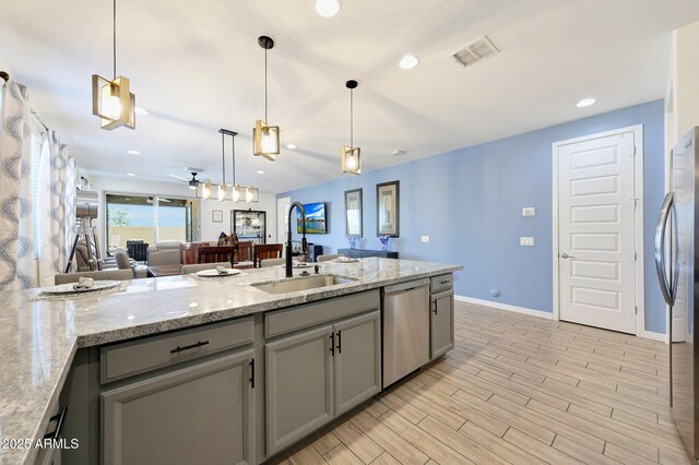 19560 W Valle Vista Way, Litchfield Park, AZ 85340 - kitchen with stainless steel appliances, a sink, open floor plan, visible vents, and gray cabinetry