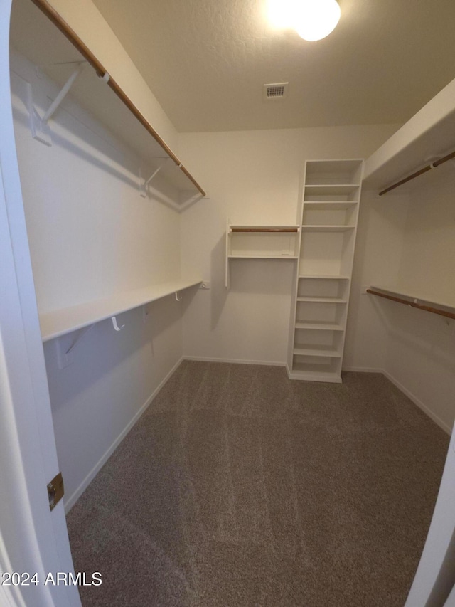 walk in closet featuring dark colored carpet