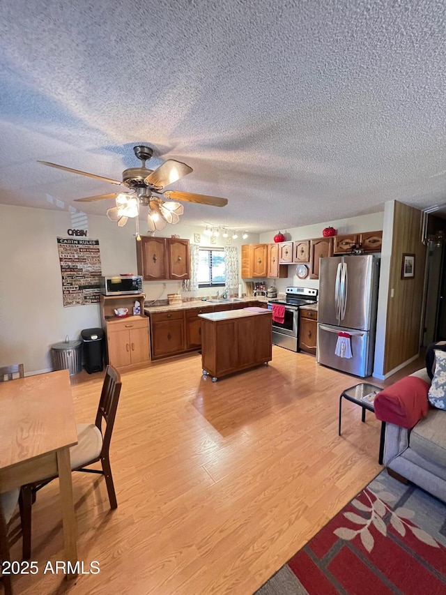 kitchen featuring a center island, a textured ceiling, light hardwood / wood-style floors, stainless steel appliances, and ceiling fan