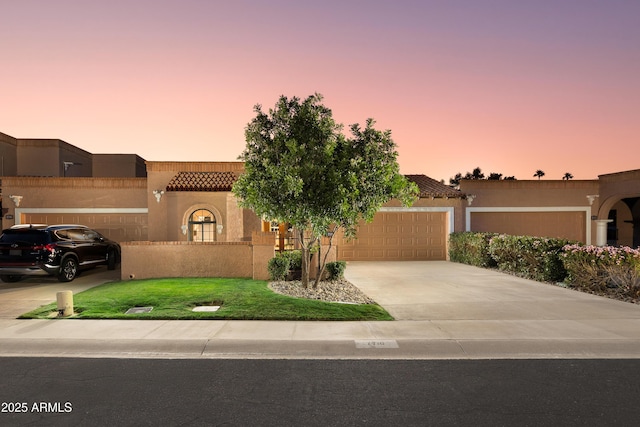view of front of home featuring an attached garage, stucco siding, concrete driveway, and a tile roof