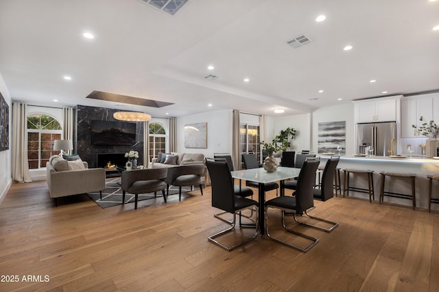 dining space with visible vents, a wealth of natural light, light wood finished floors, and a high end fireplace